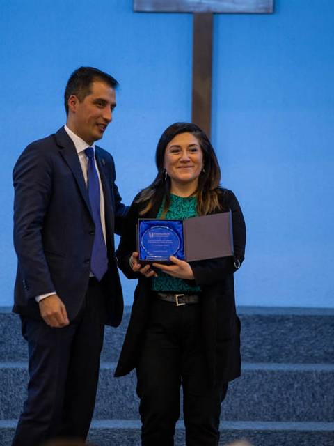 Una mujer recibe un reconocimiento de un hombre durante un evento.