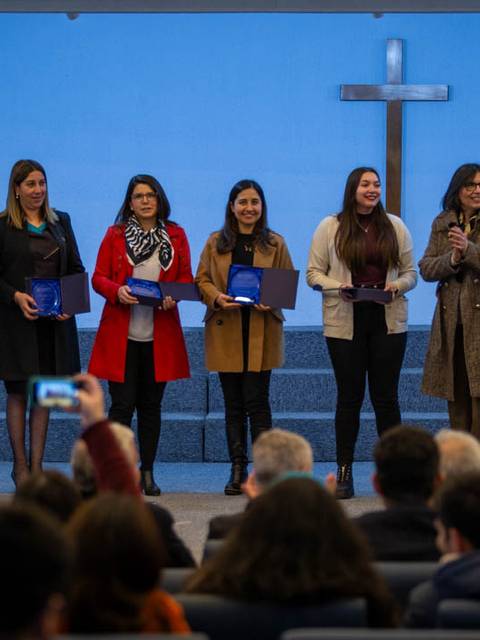 Un grupo de personas en un evento, recibiendo reconocimientos frente a una audiencia.