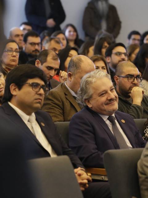 Un grupo de personas asiste a un evento en una sala llena de público.