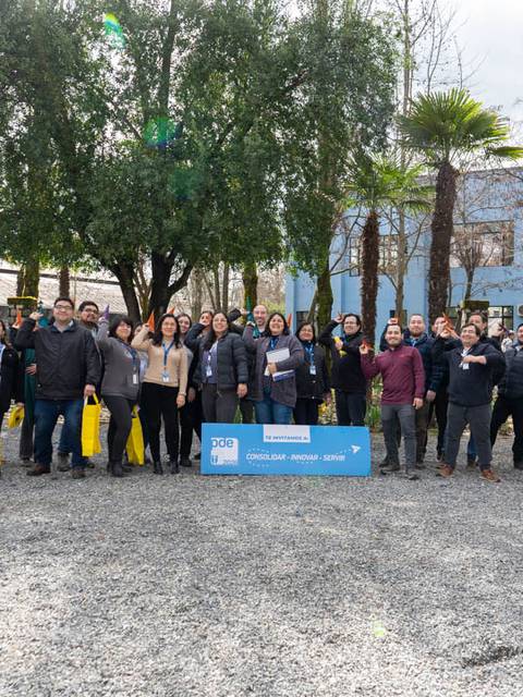 Un grupo de personas se reúne al aire libre frente a un edificio azul en un día nublado.