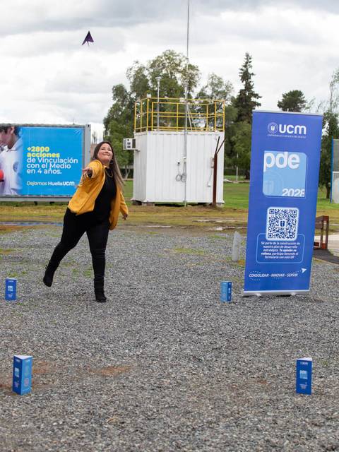 Una mujer lanza un objeto volador en un espacio al aire libre con carteles de fondo.