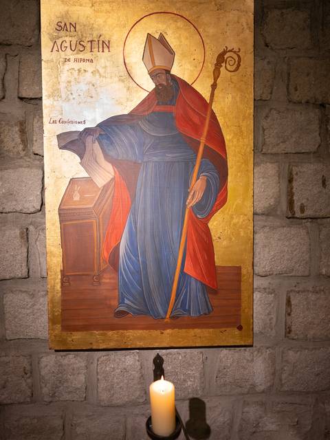 Una pintura de San Agustín con una vela encendida frente a ella.