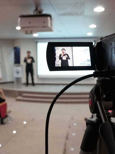 Un orador está presentando frente a una audiencia en un auditorio.