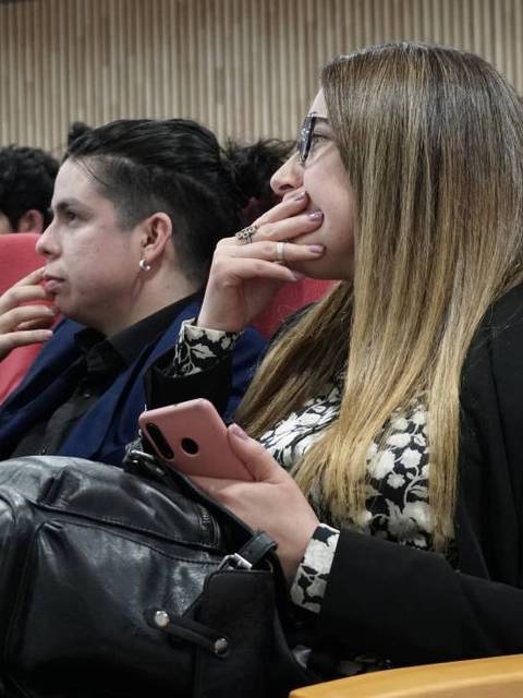 Un grupo de personas sentadas en un auditorio prestando atención.