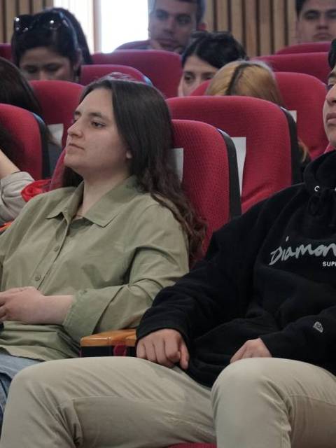Un grupo de jóvenes sentados en un auditorio escuchando atentamente.