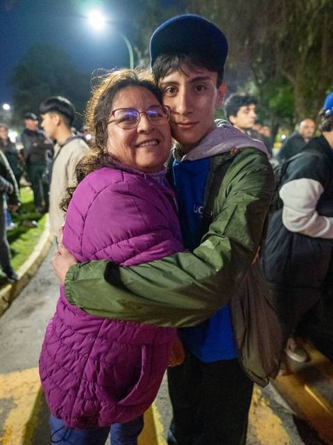 Una mujer abraza a un joven en un ambiente nocturno y festivo.