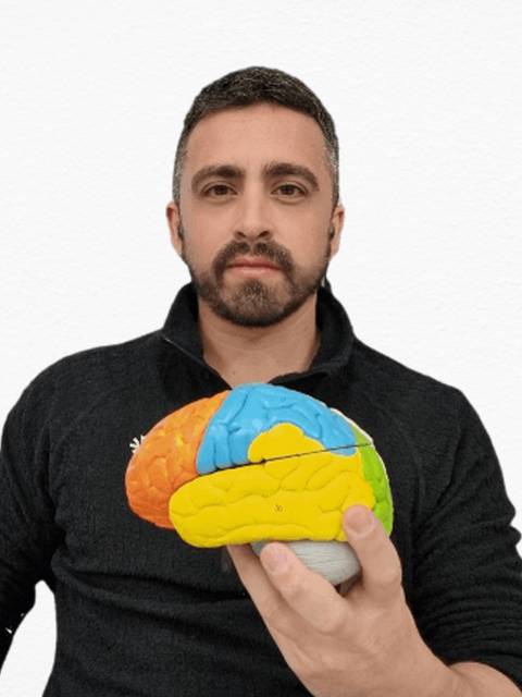 Un hombre sostiene un modelo del cerebro humano mientras sonríe a la cámara.
