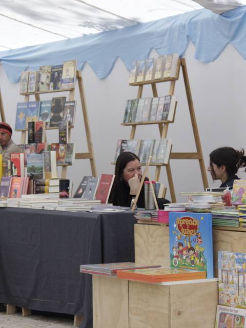 Una feria del libro con varias mesas llenas de libros y personas conversando.