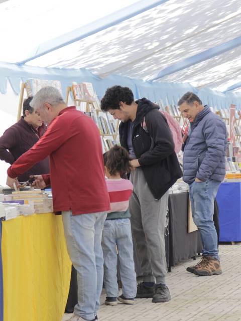 Un grupo de personas interaccionando en un mercado de libros bajo una carpa.