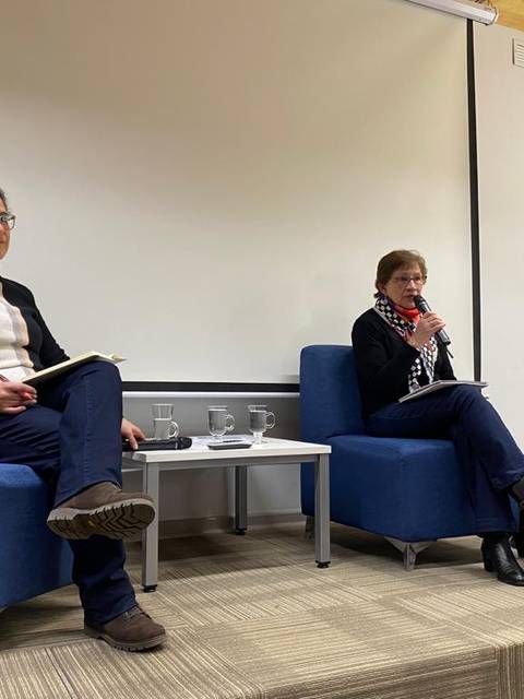 Tres personas sentadas en un panel de discusión en un ambiente sencillo.