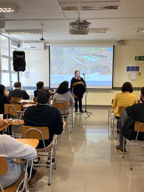 Una persona está presentando en frente de un grupo de asistentes en un salón de clases.