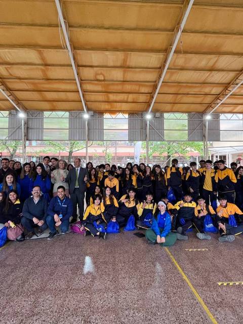 Un grupo grande de personas se reúne en un gimnasio, sonriendo y posando para la foto.