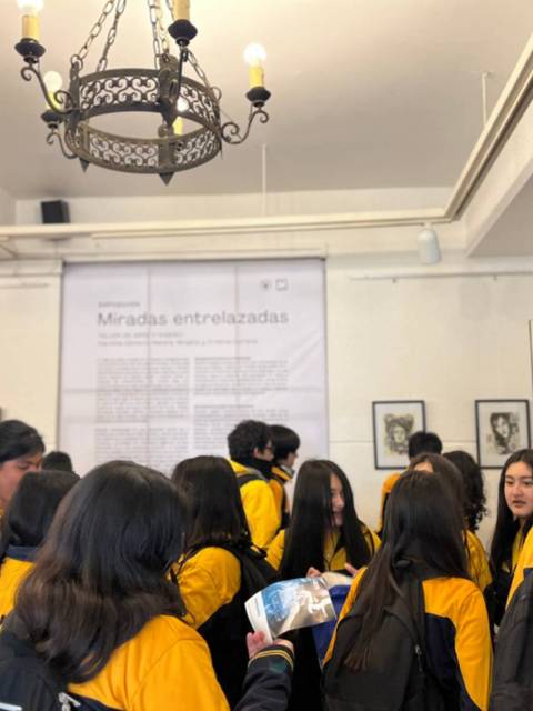 Un grupo de estudiantes con chaquetas amarillas se encuentra en una exposición en una galería.