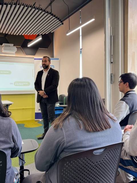 Un grupo de estudiantes escucha a un profesor en un aula moderna.