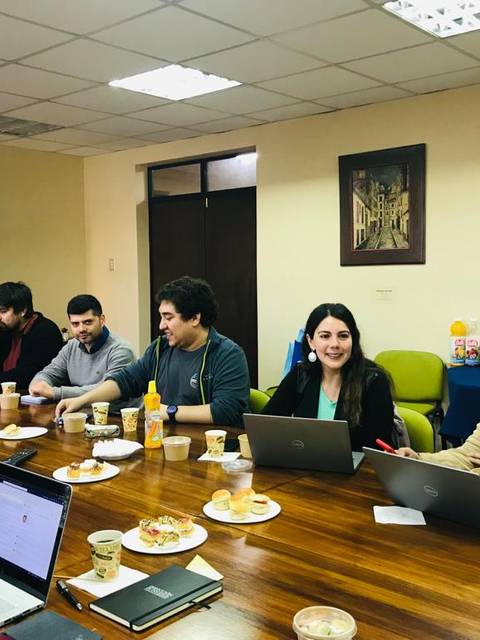 Una reunión en una sala con varias personas sentadas alrededor de una mesa en un ambiente profesional.