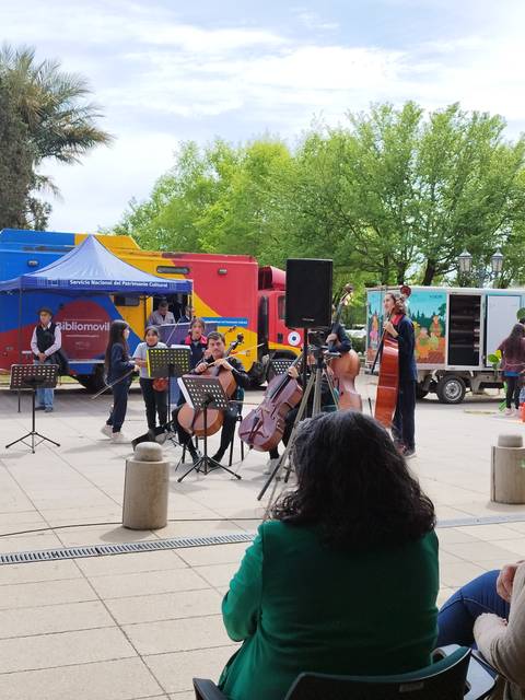 Un grupo de músicos ofrece un concierto al aire libre mientras un público atento observa.
