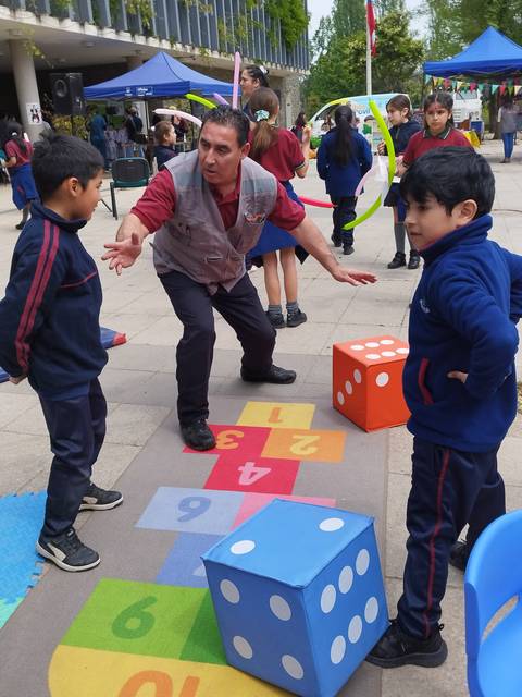 Un grupo de niños juega en una actividad al aire libre mientras un adulto les explica las instrucciones.