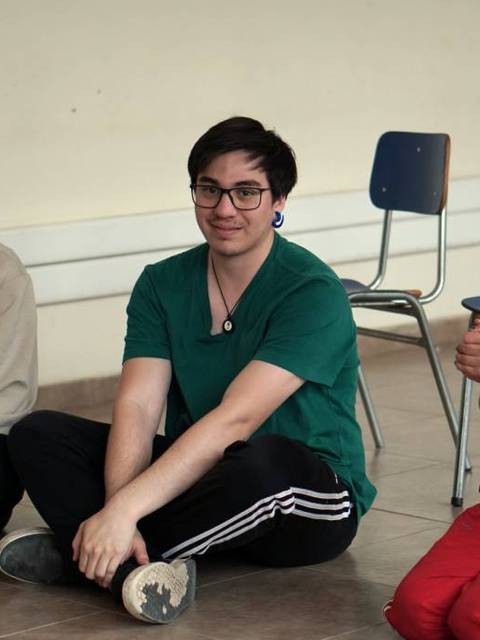 Un grupo de tres personas sentadas en el suelo, participando en una actividad en un salón.