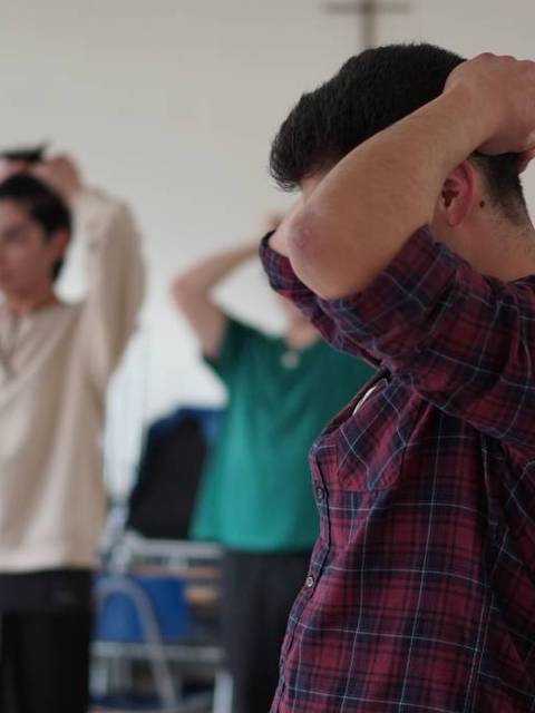 Un grupo de jóvenes realizando una actividad de estiramiento en un salón amplio.