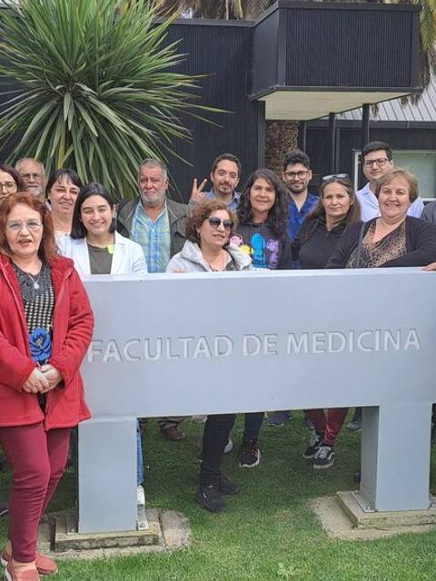 Un grupo de personas posando frente a un letrero de la Facultad de Medicina.