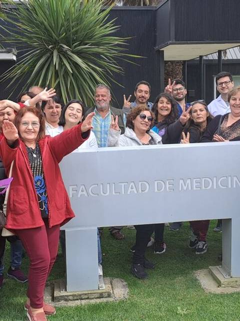 Un grupo de personas sonrientes celebra frente a un letrero de la Facultad de Medicina.