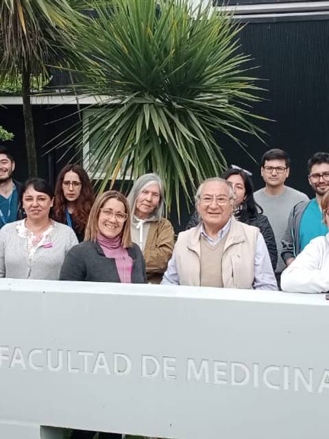 Grupo de personas posando frente a la Facultad de Medicina.