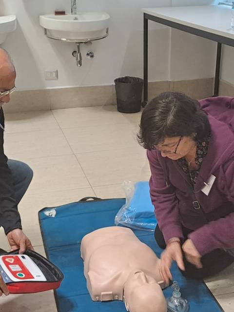 Un hombre y una mujer están practicando resucitación cardiopulmonar en un muñeco en un aula.
