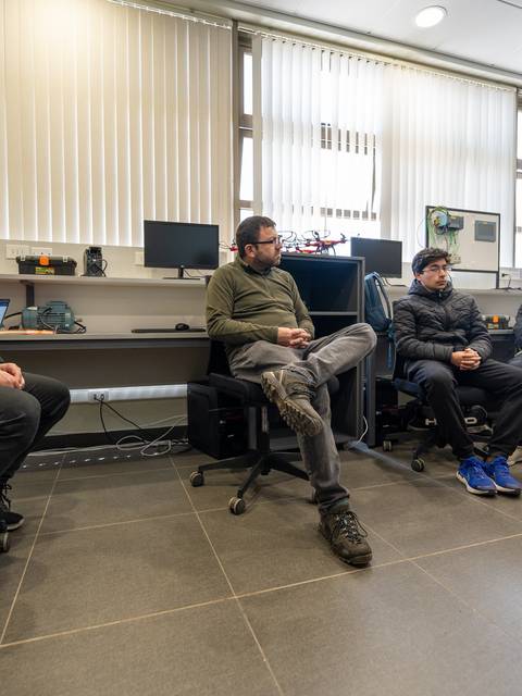 Un grupo de cinco personas sentadas en sillas frente a una pantalla en una sala de reuniones.