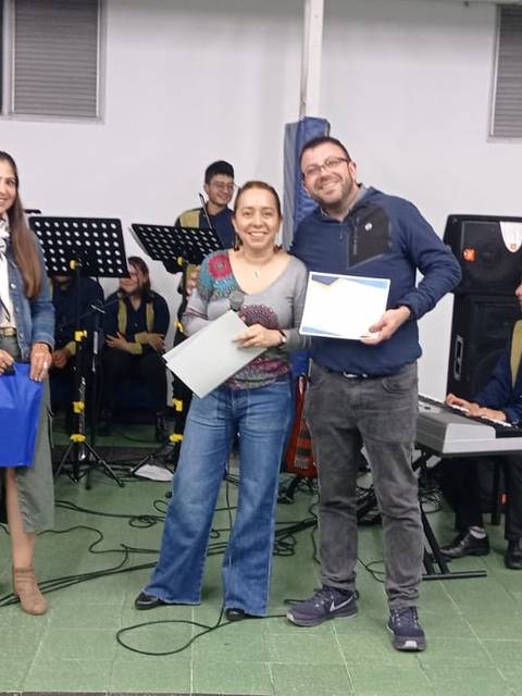 Una ceremonia de entrega de certificados con varias personas en un ambiente festivo.