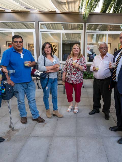 Un grupo de seis personas se encuentra de pie en un espacio exterior disfrutando de bebidas.