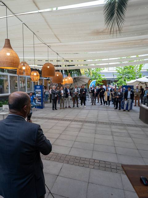 Un grupo de personas se reúne en un espacio al aire libre con toldos y decoración luminosa.