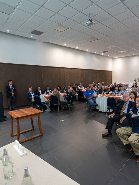 Un grupo de personas asiste a un evento donde un orador se dirige a la audiencia.