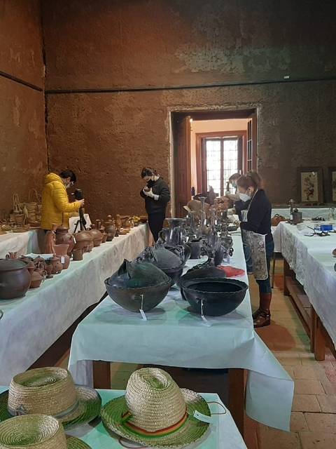 La imagen muestra un museo de cerámica con varias personas observando piezas expuestas sobre mesas blancas.