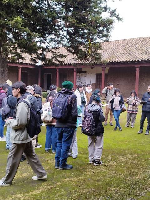 Un grupo de personas se reúne en un patio al aire libre, rodeado de edificios antiguos.