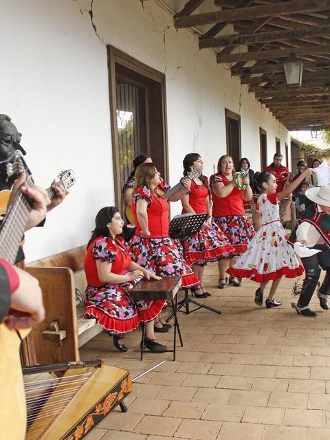 Una fiesta tradicional con música y baile, donde varias personas visten trajes típicos y disfrutan en un ambiente festivo.