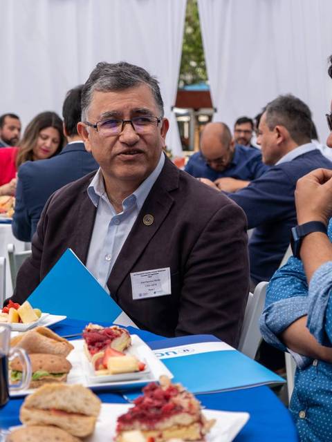 Un grupo de personas conversando en un evento, rodeados de comida y bebida.