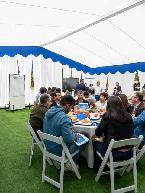 Un grupo de personas reunidas en una carpa durante un evento al aire libre.