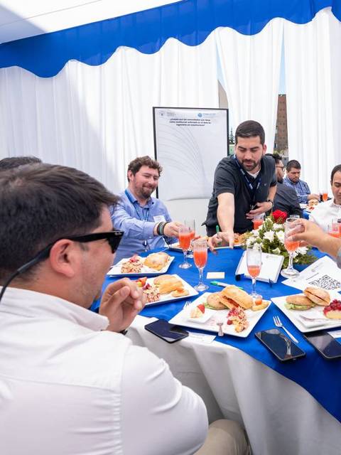 Un grupo de personas reunidas alrededor de una mesa disfrutando de una comida en un evento social.