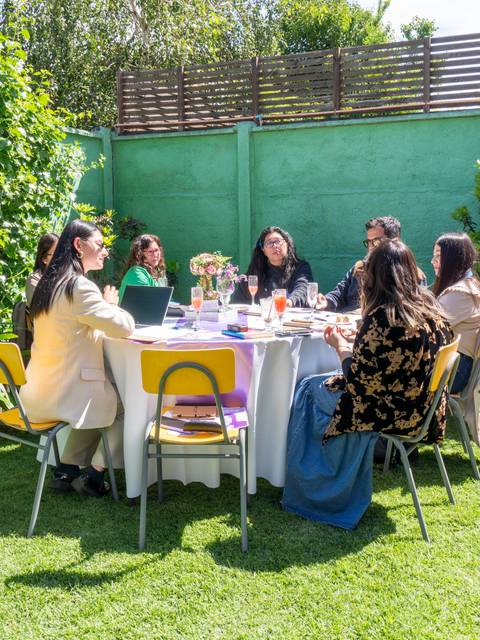 Un grupo de personas se reúne alrededor de una mesa en un ambiente al aire libre.