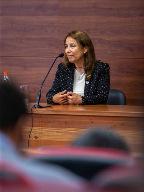Una mujer sentada en una mesa durante una conferencia.