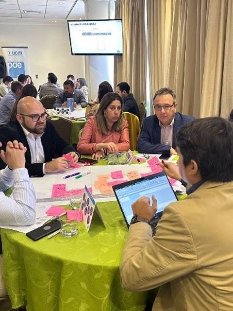 Un grupo de personas discutiendo y trabajando en una mesa durante una reunión.