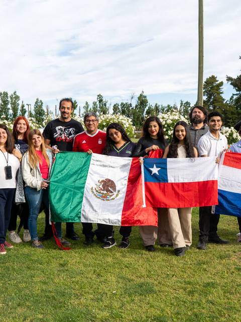 Grupo de personas sosteniendo banderas de México, Chile y Paraguay en un parque.