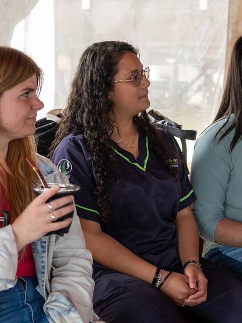 Tres jóvenes conversando mientras sostienen termos en un ambiente acogedor.