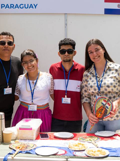 Cuatro personas sonríen detrás de una mesa decorada con platos típicos de Paraguay.