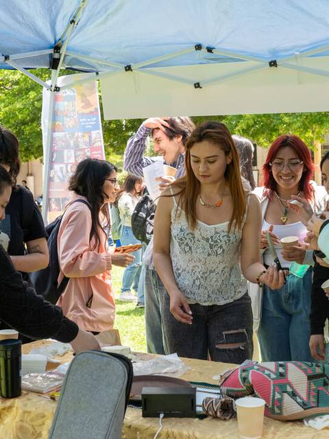 Un grupo de personas interactuando en un evento al aire libre bajo una carpa.