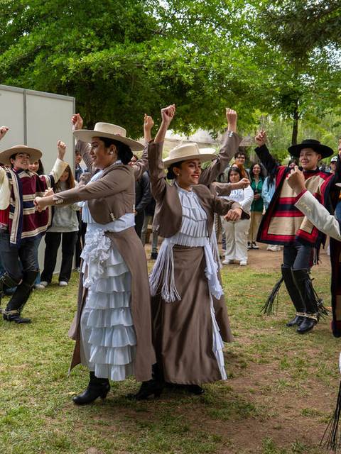 Un grupo de personas bailando y disfrutando en un evento al aire libre, vestidos con trajes típicos.