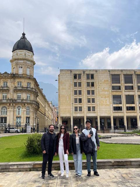 Fotografía de un grupo de cuatro personas posando en una plaza con arquitectura histórica en Bogotá.