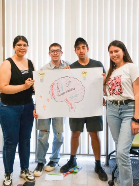 Cuatro estudiantes sosteniendo un cartel sobre la responsabilidad en un aula.