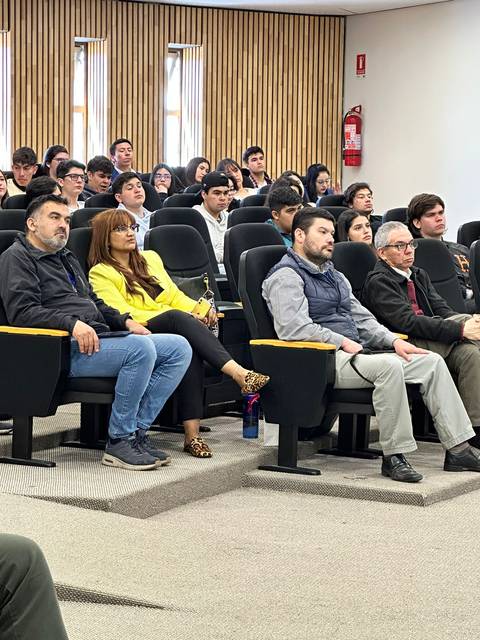 Un grupo de personas sentadas en una sala de conferencias escuchando una presentación.