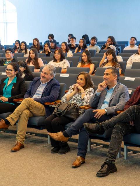 Un grupo de personas sentadas en un auditorio durante un evento.